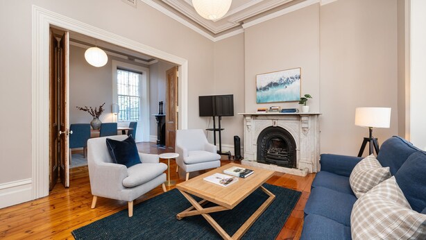A living room with a fireplace, two armchairs, a sofa, a coffee table, and a TV. - Saint Francis in Fitzroy (Fitzroy)