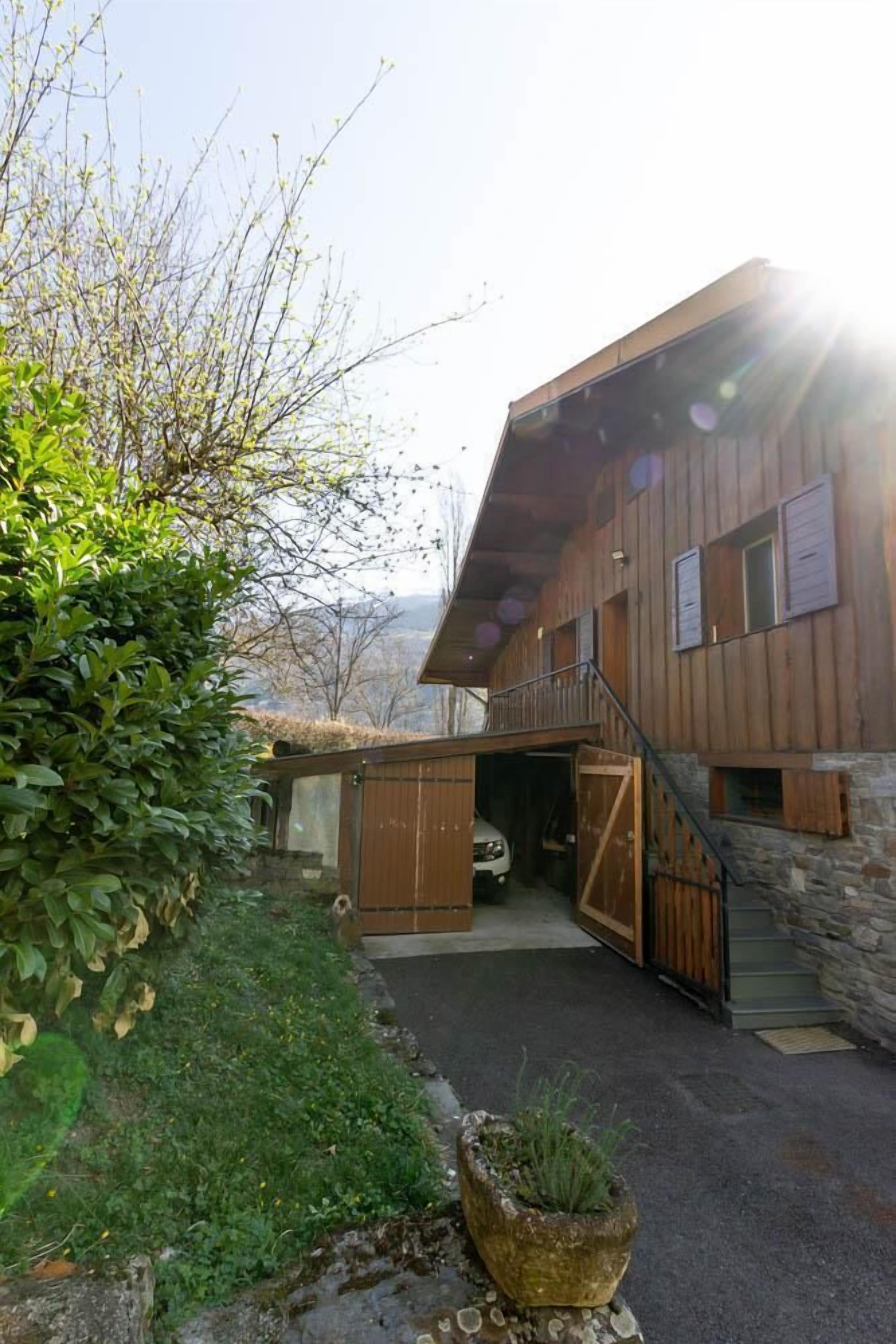 Un bâtiment en bois, doté de fondations en pierre, d’une entrée couverte et d’un escalier menant à un deuxième étage.