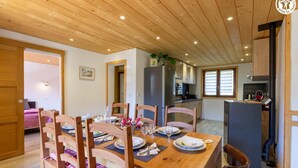 A dining area with wooden furniture, a kitchen in the background, and a visible door leading to another room. - LE CHALET D'YVETTE - LA PLAGNE TARENTAISE (LA PLAGNE TARENTAISE)