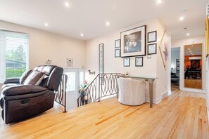 A spacious living area with a leather recliner, a glass coffee table, and a staircase leading to an upper level. - Laval: Private Heated Pool • 3 Bedrooms • Piano (Laval)
