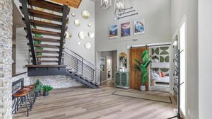 Ein geräumiger Innenbereich mit Treppe, Holzboden und einer Sitzecke mit Tischen und Stühlen.