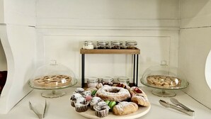 Una exposición de postres con diferentes pasteles y una pequeña estantería con frascos.