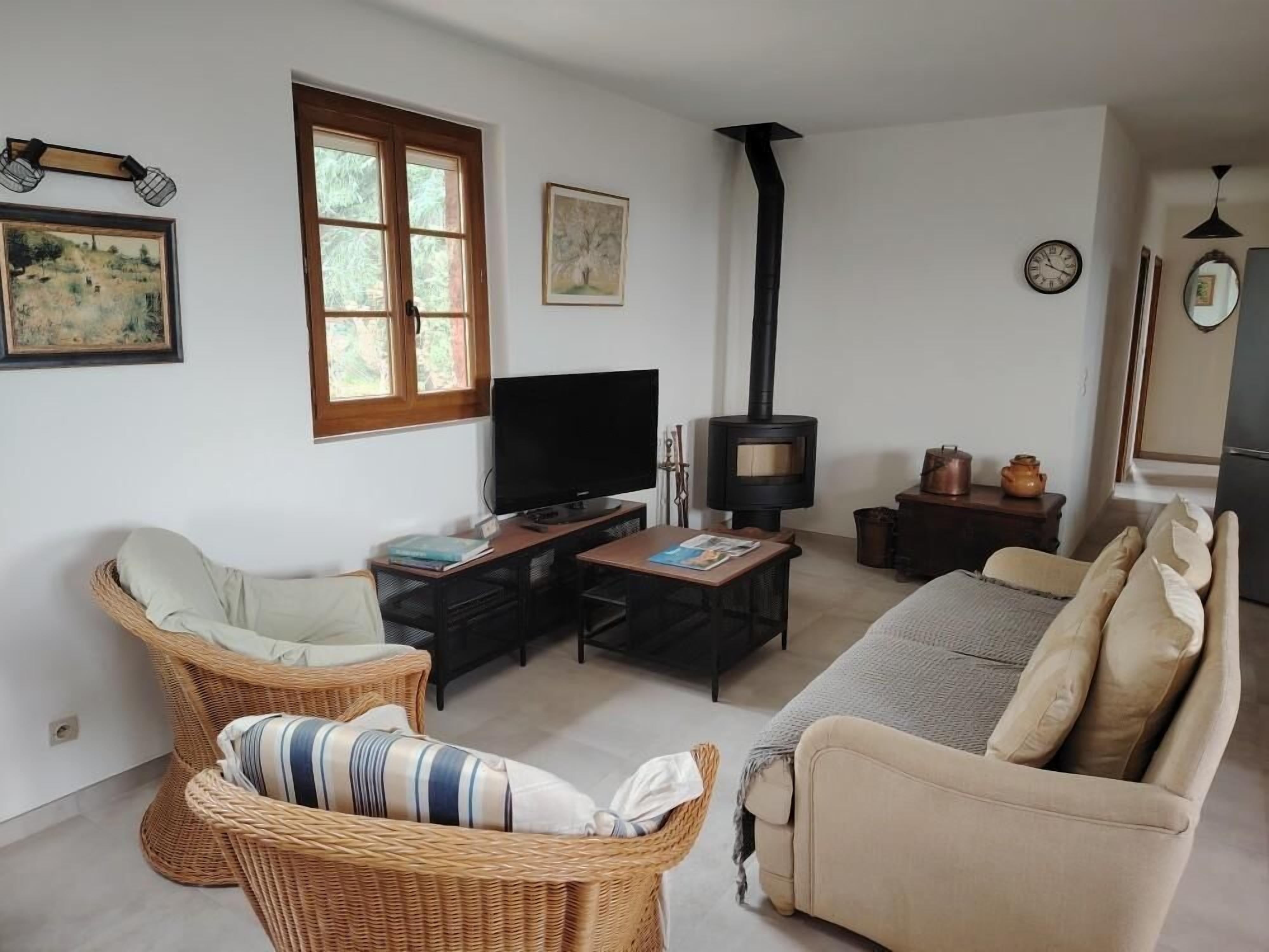 A cozy living room with wicker furniture, a flat-screen TV, a fireplace, and artwork on the walls.