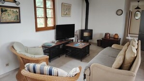 A cozy living room with wicker furniture, a flat-screen TV, a fireplace, and artwork on the walls. - LE PERCHOIR - LES MAYONS (LES MAYONS)