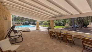 Une terrasse extérieure avec une piscine, des sièges et un espace barbecue.
