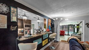 A modern kitchen with a bar area, bar stools, and a dining table. - 6mi from AT&T-HEATED POOL-HOT TUB-INDOOR BAR-TOP KITCHEN AMENITIES-SLEEPS 12+ (Arlington)
