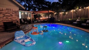 A swimming pool with inflatable loungers and a covered seating area. - 6mi from AT&T-HEATED POOL-HOT TUB-INDOOR BAR-TOP KITCHEN AMENITIES-SLEEPS 12+ (Arlington)