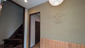 A staircase leading to a room with a wooden floor, a door with a handle, and a wall with a circular design. - Tradition x Style 9ppl Rooftop Home near ShinOsaka (大阪市)