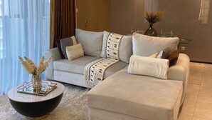 A modern living room with a sectional sofa, a round coffee table, and a decorative vase. - Chic 1-bedroom apartment in wonderful Nairobi with AC, fitness room, WiFi (Nairobi)
