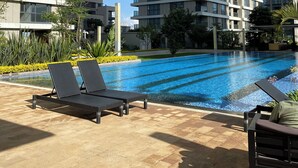 A modern hotel with a swimming pool, lounge chairs, and high-rise buildings in the background. - Chic 1-bedroom apartment in wonderful Nairobi with AC, fitness room, WiFi (Nairobi)
