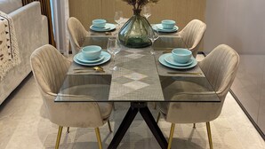 A dining area with a glass table, four chairs, and a vase with dried plants. - Chic 1-bedroom apartment in wonderful Nairobi with AC, fitness room, WiFi (Nairobi)