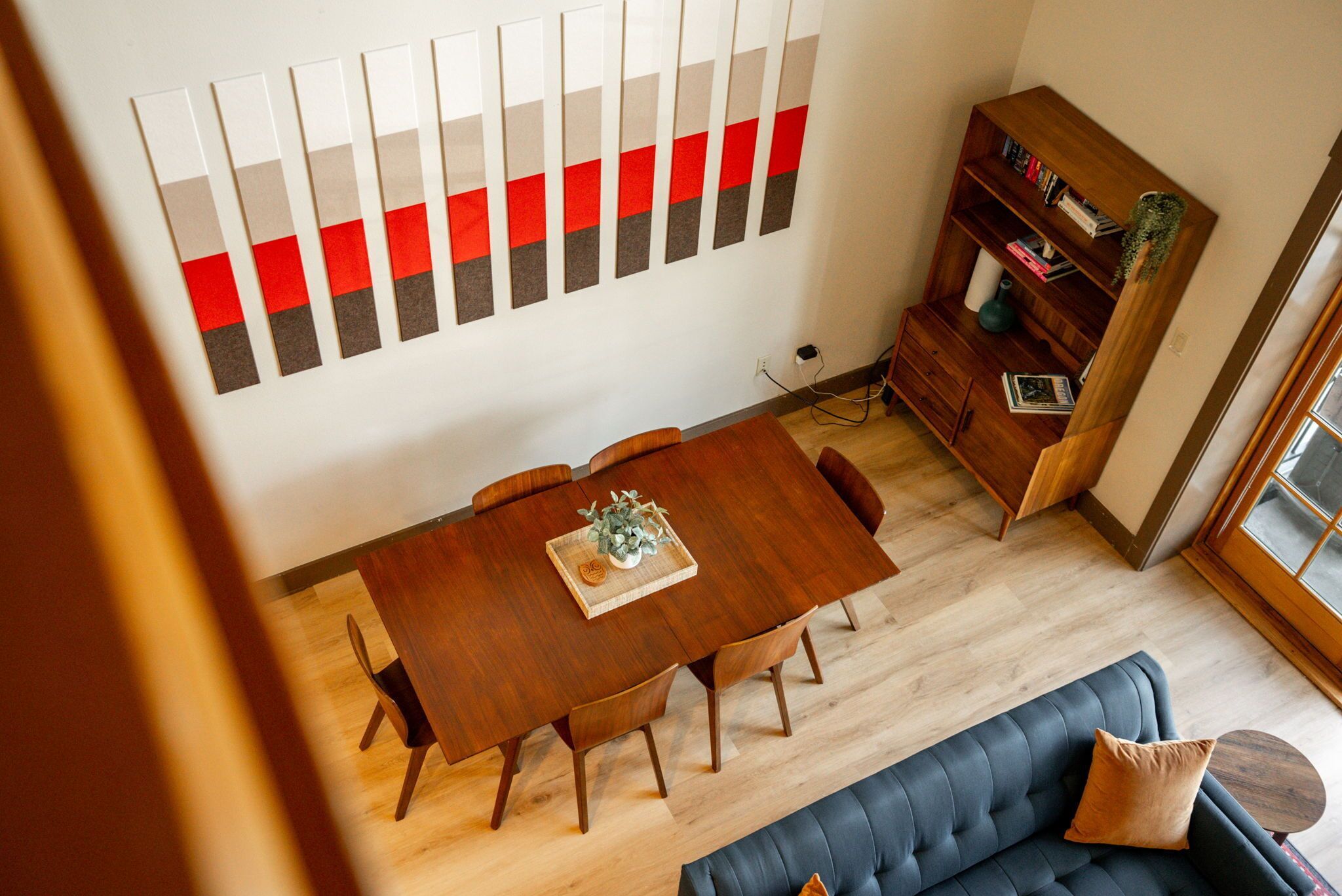A dining area with a wooden table and chairs, a bookshelf, and a sofa.