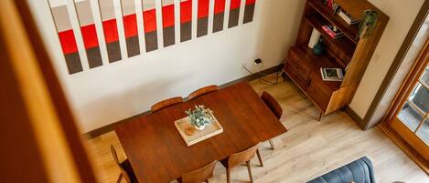 A dining area with a wooden table and chairs, a bookshelf, and a sofa.