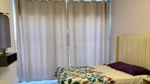 Une chambre à coucher moderne avec un lit, une tête de lit, un téléviseur fixé au mur et un luminaire au plafond.