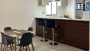 Une cuisine moderne dotée d’un îlot central, de tabourets de bar et de luminaires suspendus.