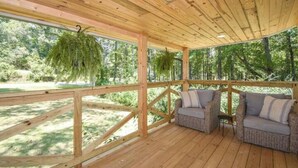 Una terraza de madera con mobiliario de mimbre y plantas colgantes.