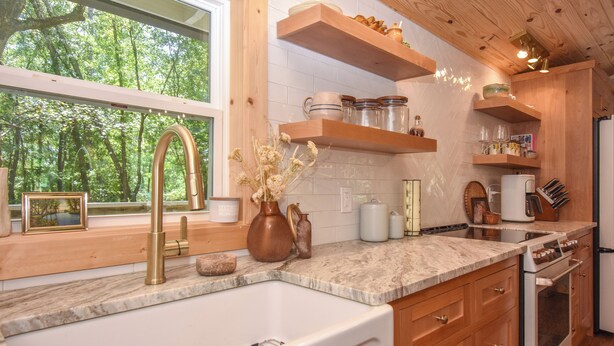 Una cocina con un ventanal grande, estanterías de madera y un horno empotrado.