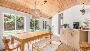 A modern kitchen with wooden cabinets, a large wooden table, and a hanging plant. - Remodeled 2-bedroom house with hot tub, 7mins to Saugatuck & beach (Fennville)
