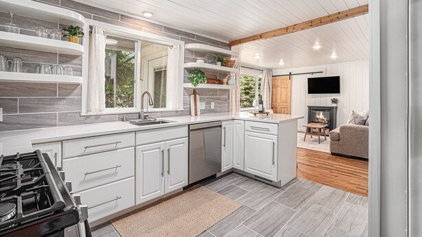 A modern kitchen with white cabinetry, a built-in stove, and a large window. - Remodeled 2-bedroom house with hot tub, 7mins to Saugatuck & beach (Fennville)