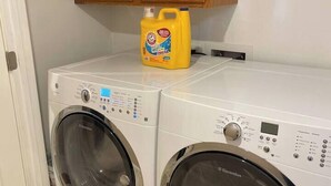 Ein Waschbereich mit zwei Waschmaschinen und einer Flasche Waschmittel darauf.