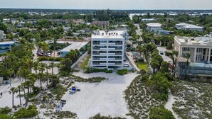 Un hotel de diverses plantes amb un pati central, envoltat de palmeres i una zona de platja de sorra.