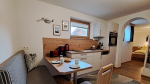 A compact kitchen with a wooden countertop, a dining table, and a built-in oven.