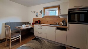 A compact kitchen with a wooden countertop, a built-in oven, and a sink. There is a dining area with a striped sofa and a chair.