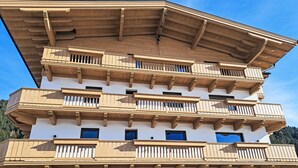 A multi-story building with wooden balconies and large windows.