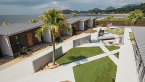 Un complexe hôtelier moderne doté d’une piscine, d’un espace extérieur aménagé et offrant une vue sur la mer.