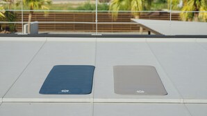 Deux tapis de yoga sur une terrasse en toit, avec vue sur des palmiers et une plage en arrière-plan.