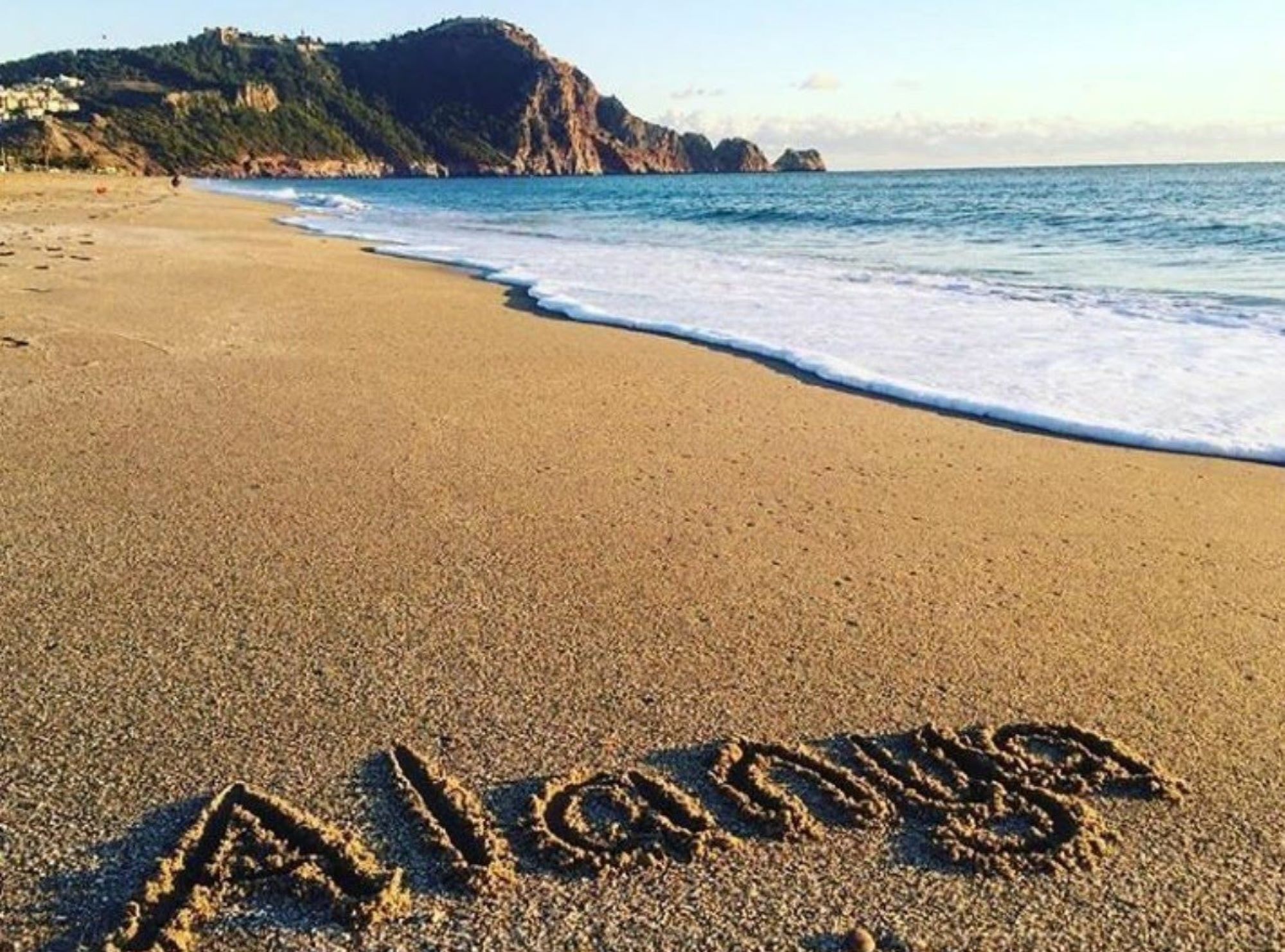 En strand där ordet ”Alanya” är skrivet i sanden.