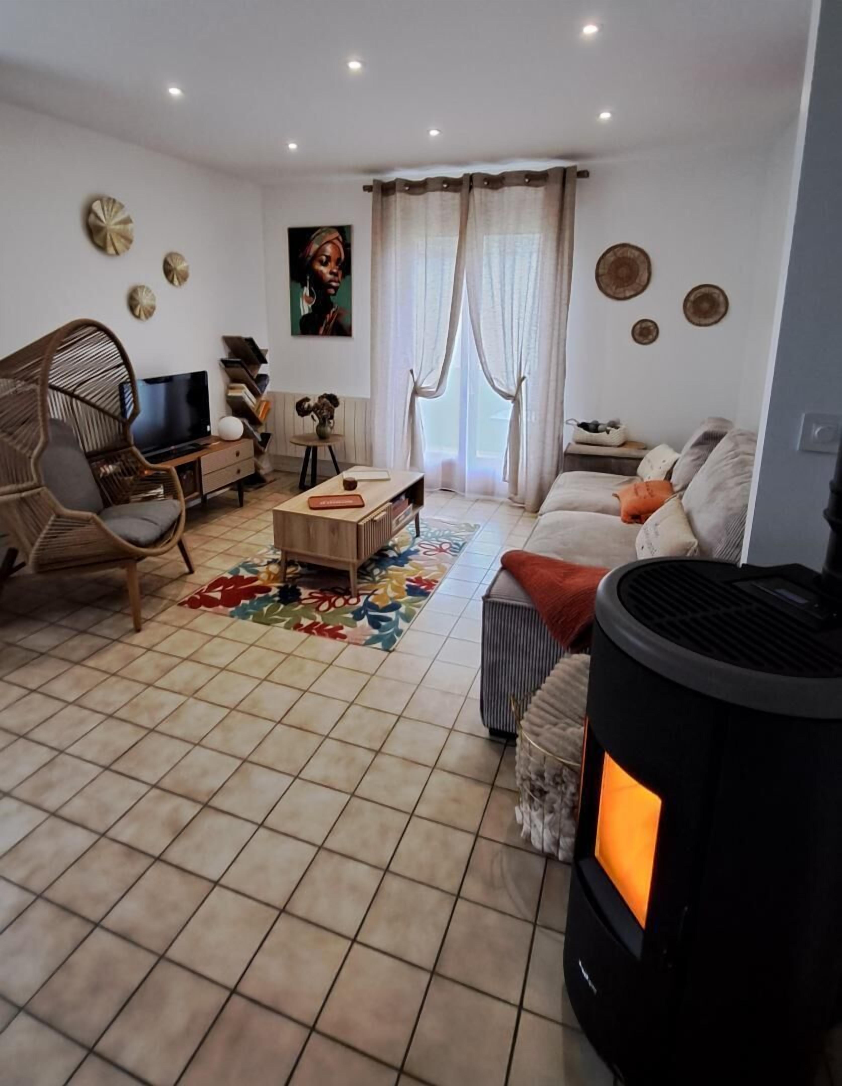 Een woonkamer met een bank, een stoel, een televisie, een open haard en een vloerkleed.