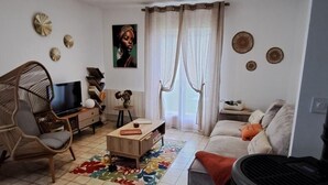 Un salon avec un canapé, un fauteuil, une télévision, une cheminée et un tapis.