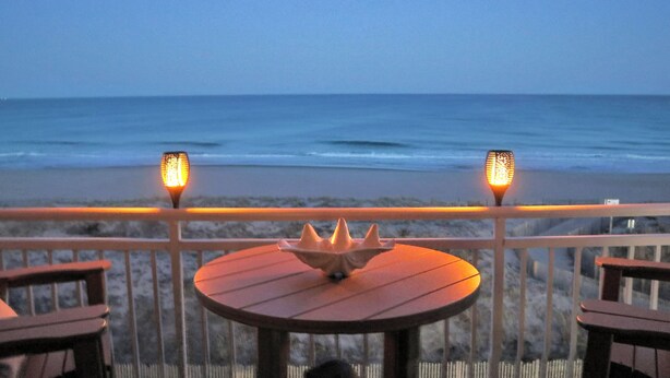 A beachside table with a decorative centerpiece, two lanterns, and a view of the ocean. - BeachBox III • Unreal Views • Oceanfront Balcony • Couple's Getaway (Ocean City)