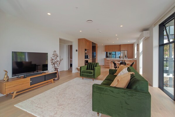 Ein geräumiger Wohnbereich mit einem großen Flachbildfernseher, einem grünen Sofa und einer Holz-Unterhaltungsanlage.