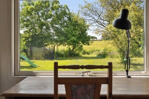 A room with a view of a green slide, a wooden chair, and a desk.