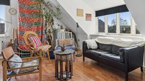 Un salon chaleureux avec un canapé en cuir noir, une chaise en bois, un tapis à motifs et une petite table ronde.