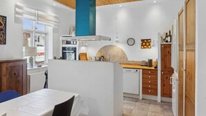 Une cuisine moderne avec des meubles blancs, une cheminée bleue et un coin repas comprenant une table et des chaises.