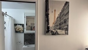 A bathroom with a white sink, a mirror, and a framed cityscape photograph on the wall. - CozyMiniStudio (Vancouver)
