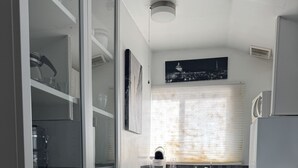 A compact kitchen with a dishwasher, microwave, and refrigerator. - CozyMiniStudio (Vancouver)