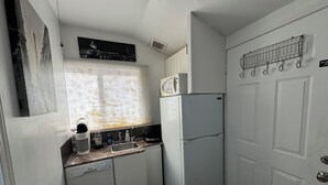 A compact kitchen with a built-in dishwasher, a microwave, and a refrigerator. - CozyMiniStudio (Vancouver)
