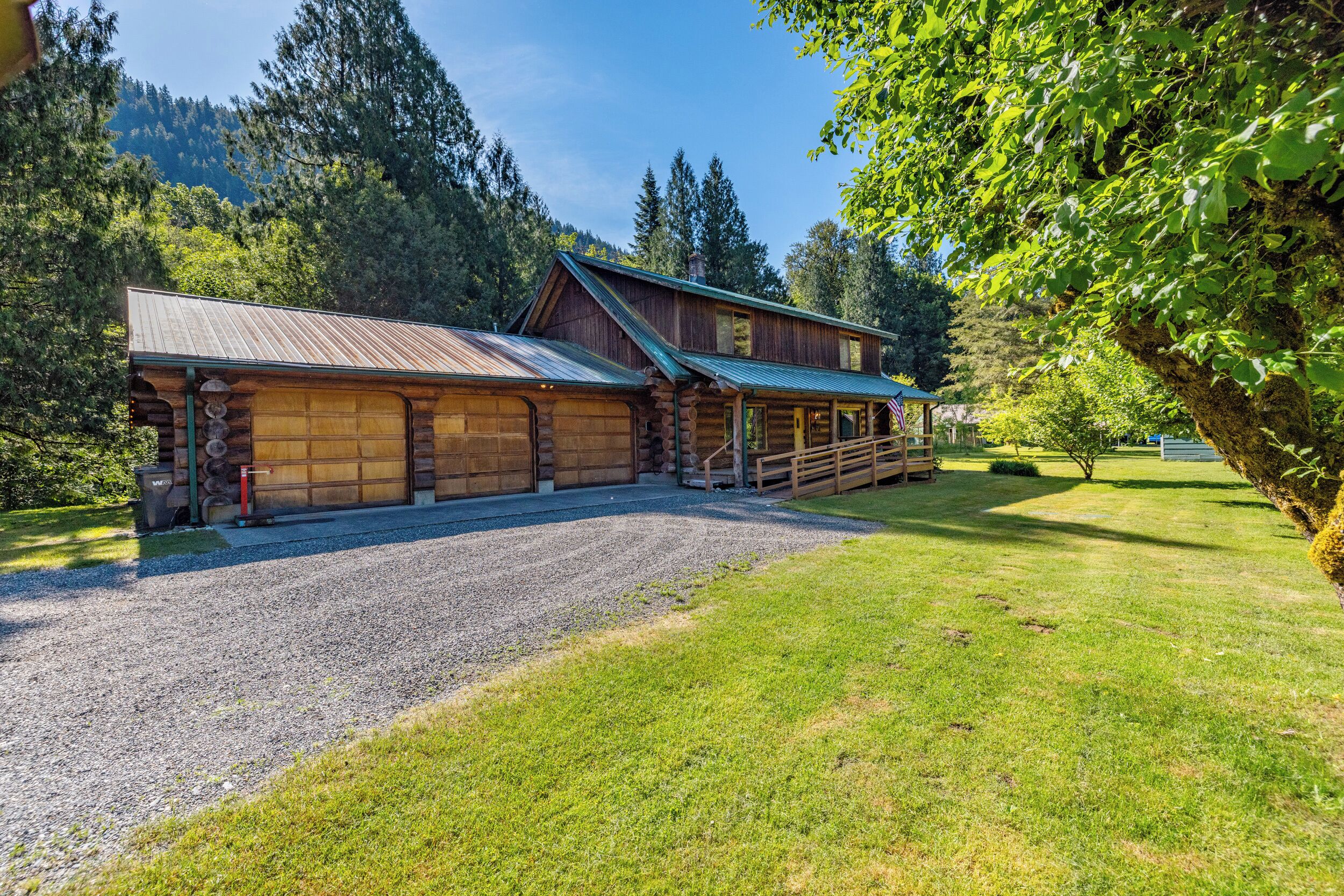 A log cabin with a gravel driveway and a fenced yard.