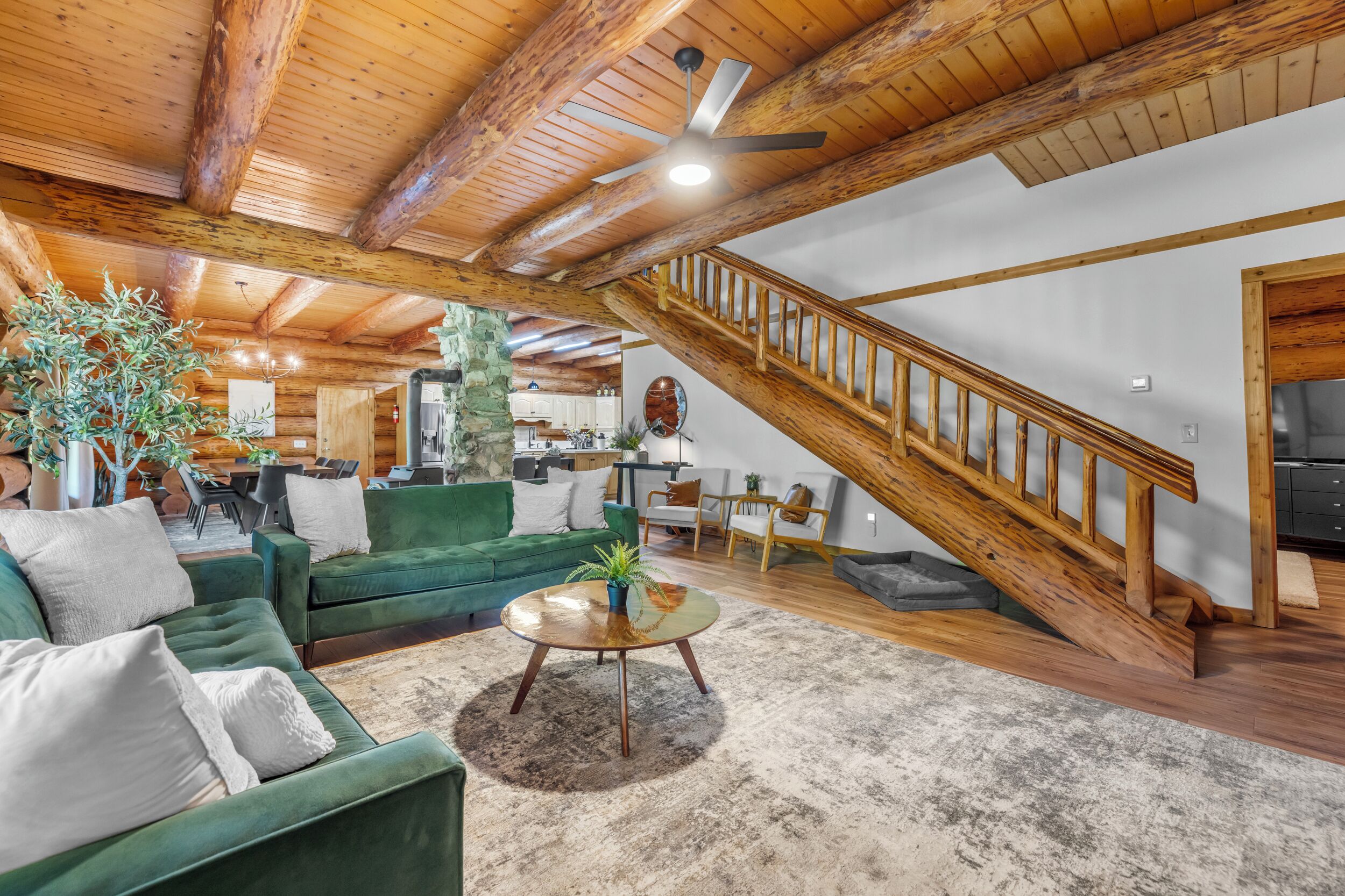 A spacious living area with a green sofa, a coffee table, and a staircase leading to an upper level.