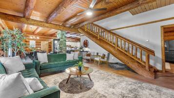 A spacious living area with a green sofa, a coffee table, and a staircase leading to an upper level.