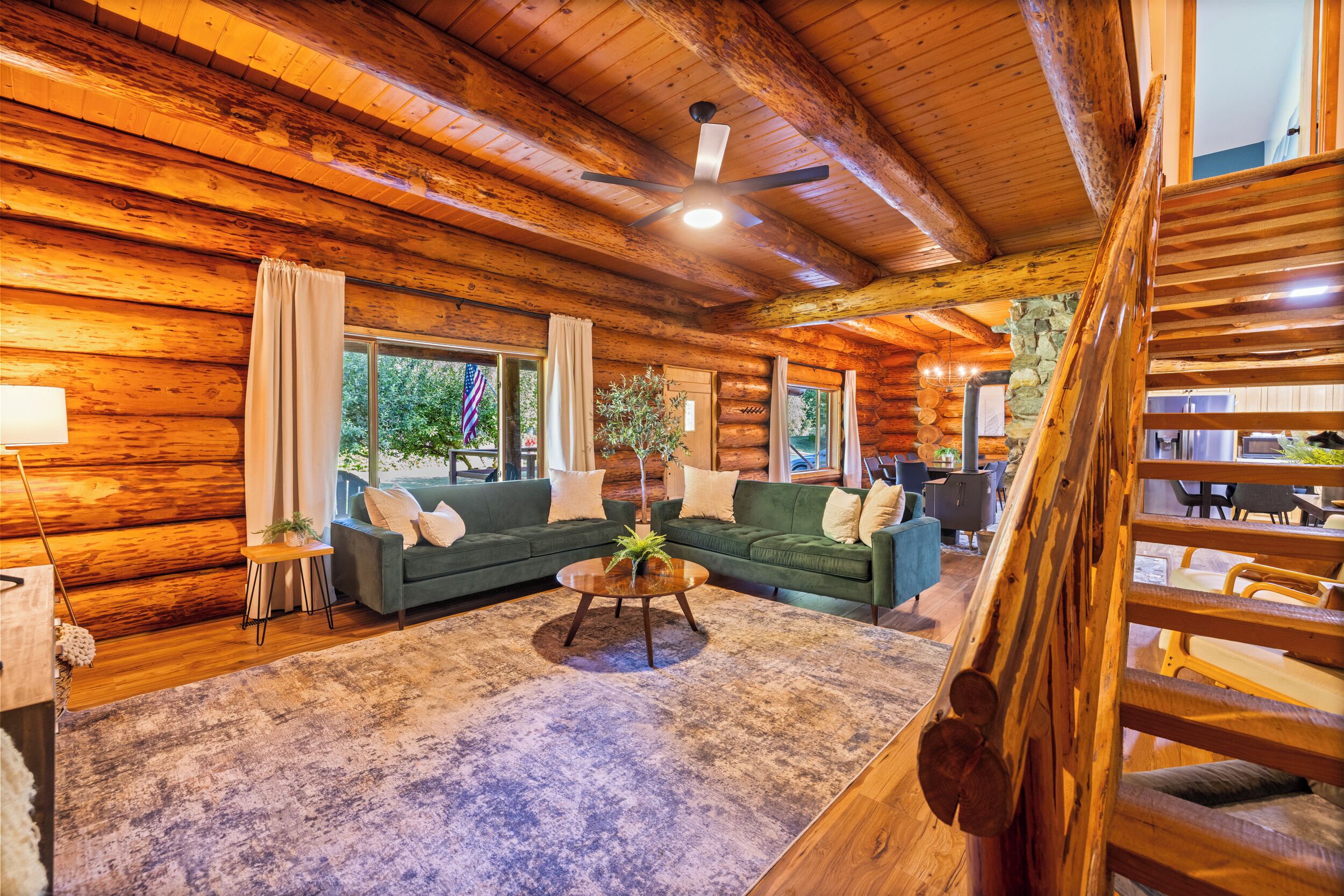 A log cabin interior with a green sofa set, a coffee table, and a stone wall.