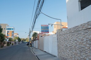 A street view with a sign for an apartment hotel, a gated entrance, and residential buildings. - BNB Family Budget Hotel (Santo Domingo Este)