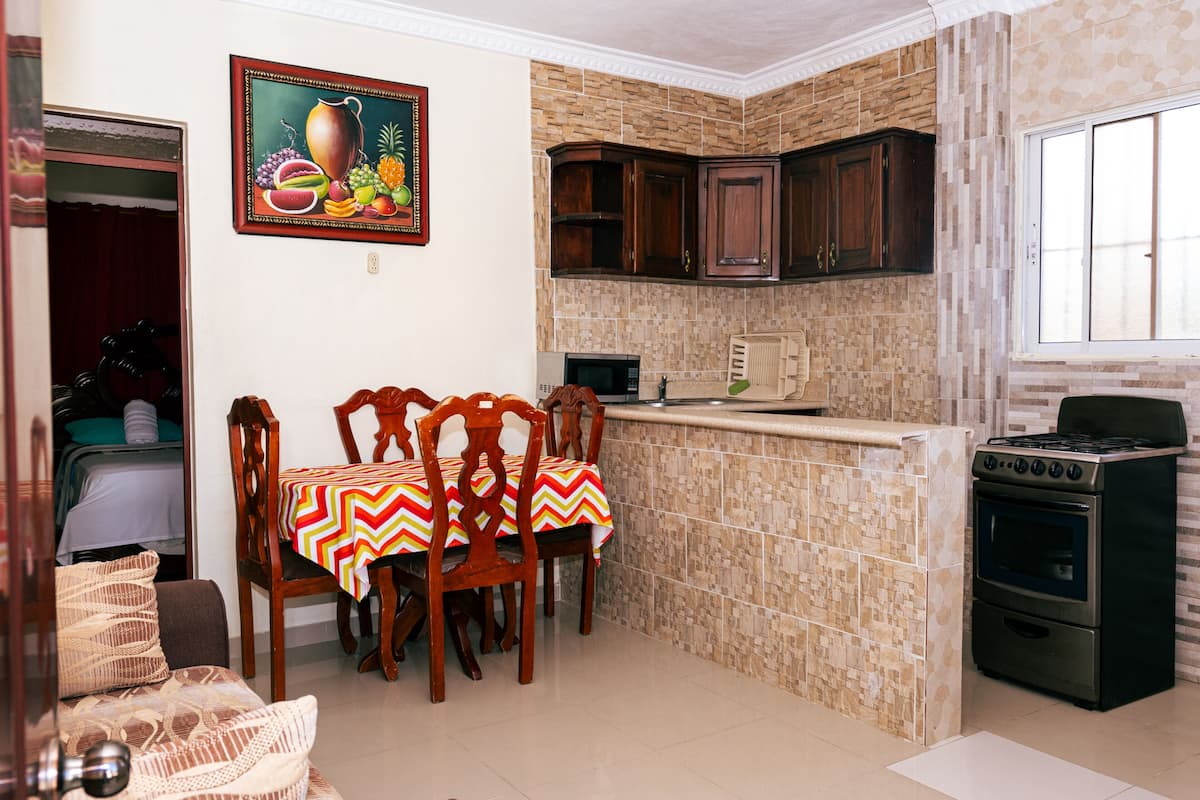 A compact kitchen with a dining area, a microwave, a stove, and a tiled backsplash.