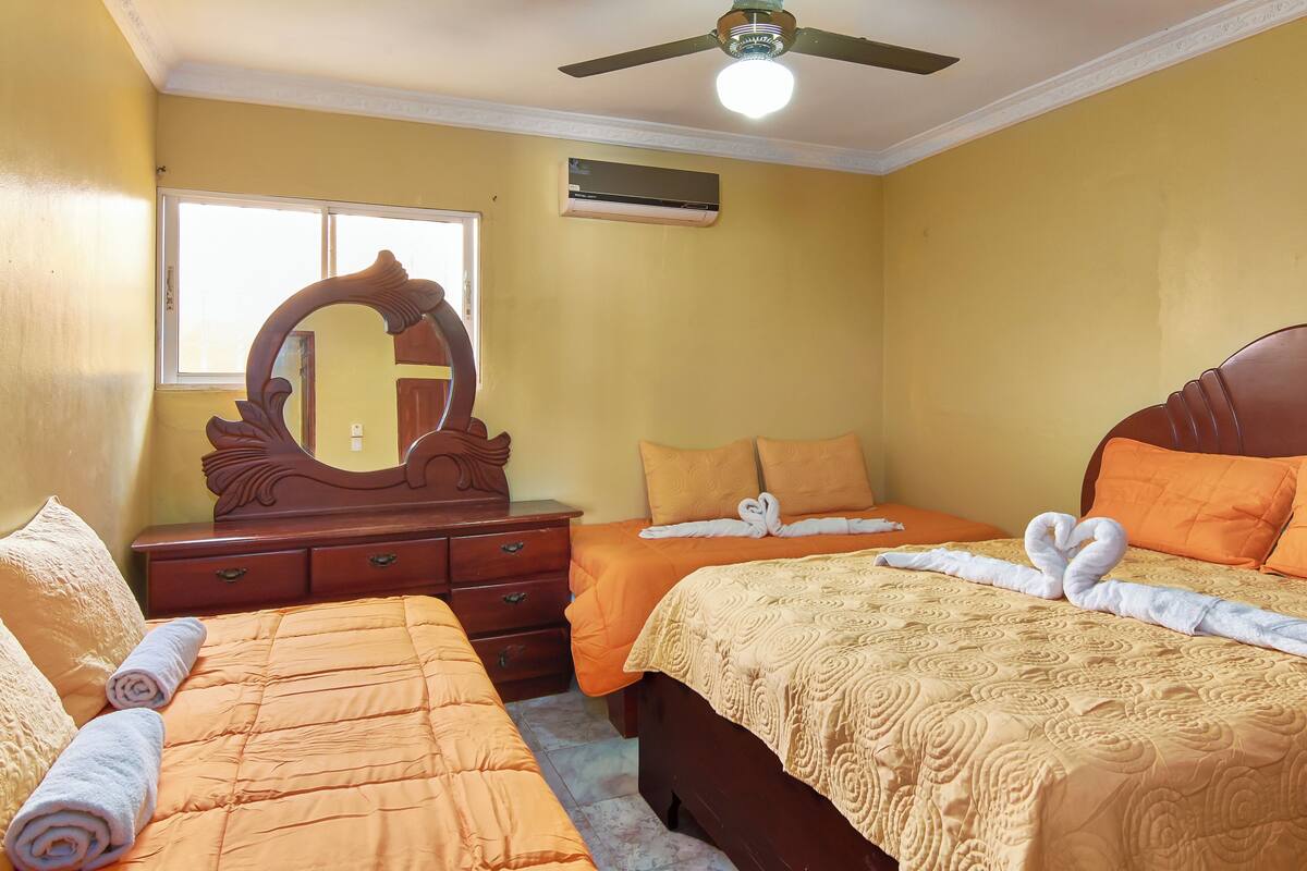 A hotel room with two beds, a large mirror, and a ceiling fan.