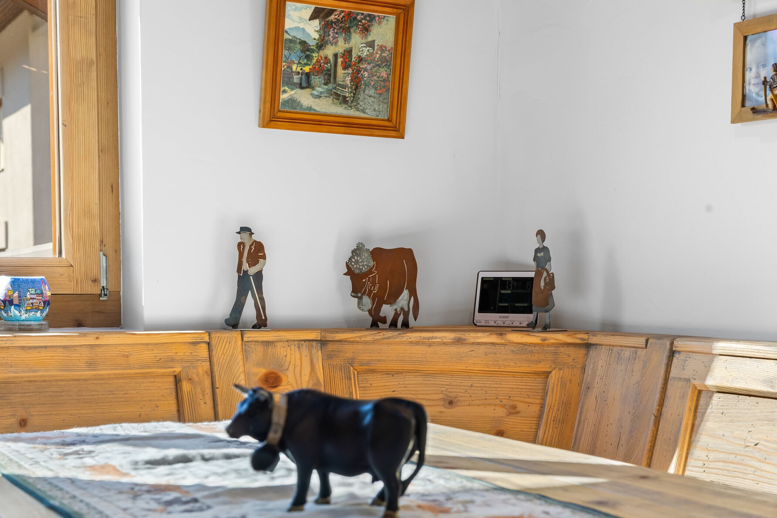 Une pièce avec un meuble en bois, un tableau et des figurines accrochées au mur.