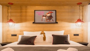 A wooden-paneled bedroom with a bed, two pillows, a framed picture, and two pendant lights. - Apartment in Megeve With Stunning Mountain Views (Megeve)